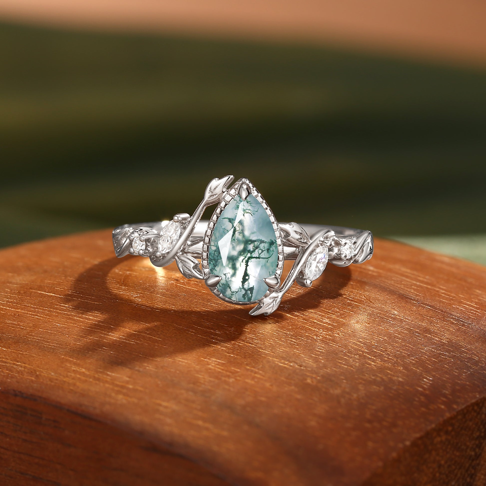 Gold ring with a green moss agate gemstone on a wooden surface