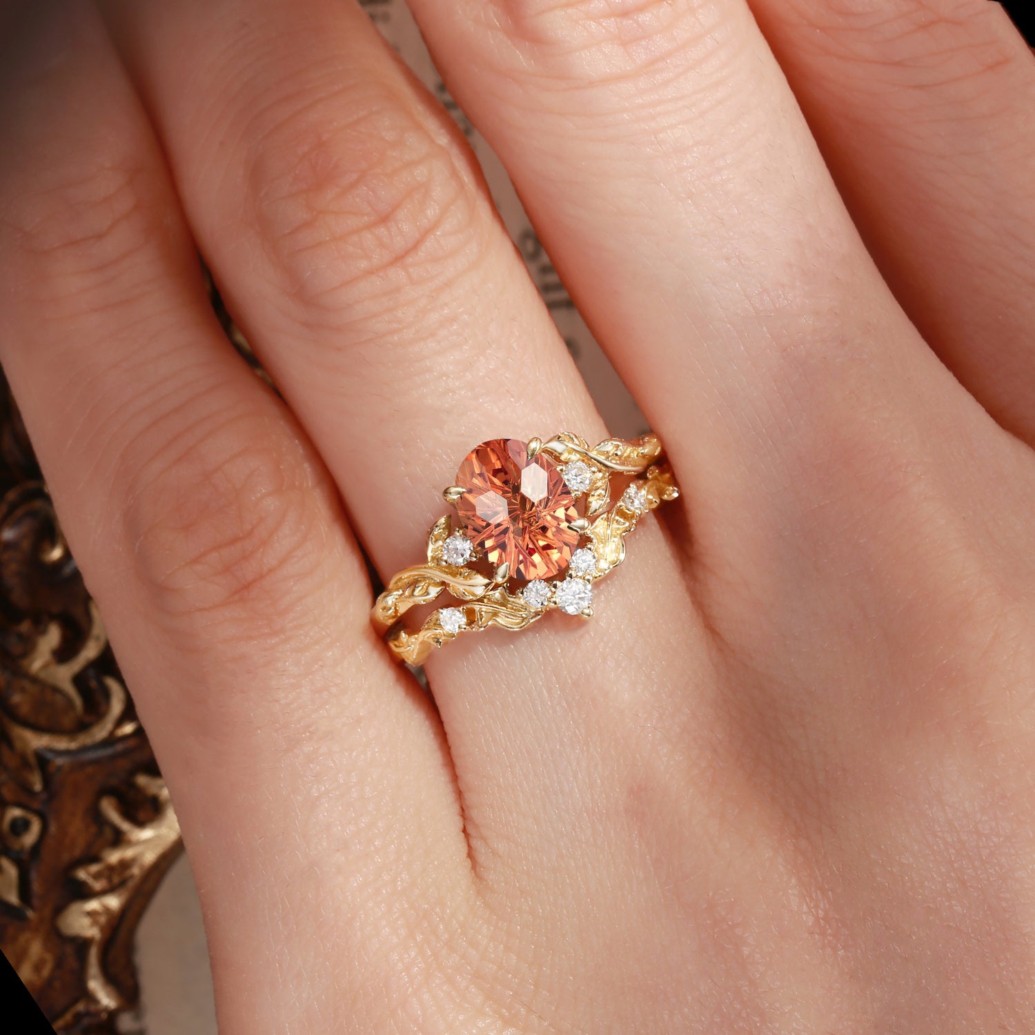 Gold ring with a large orange gemstone on a hand